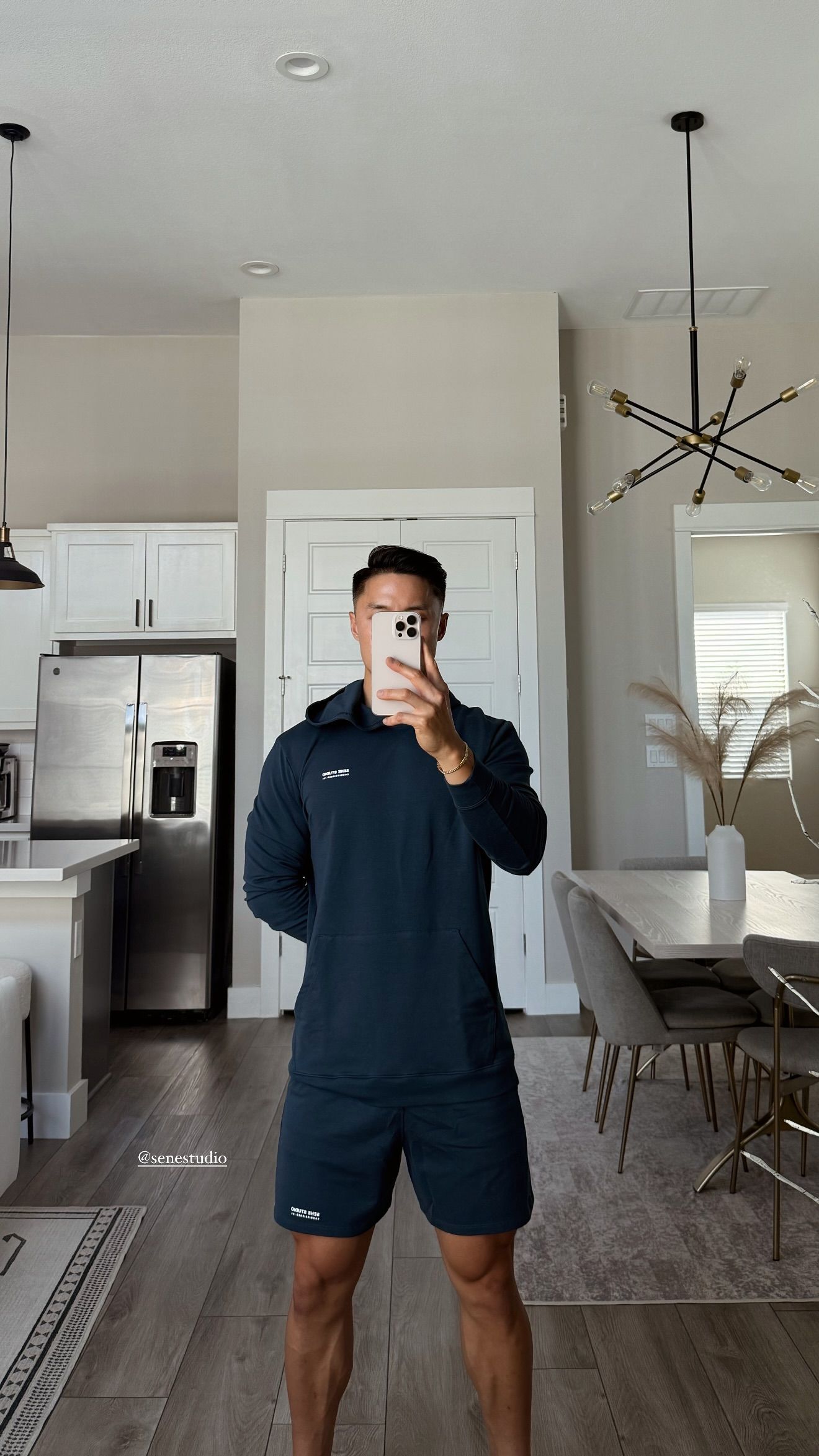 Person taking mirror selfie in a modern kitchen-living area.